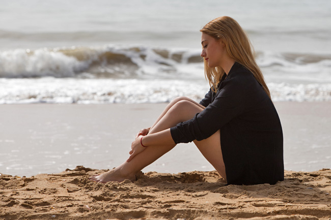 Beautiful young blonde woman on the beach sad and depressed.