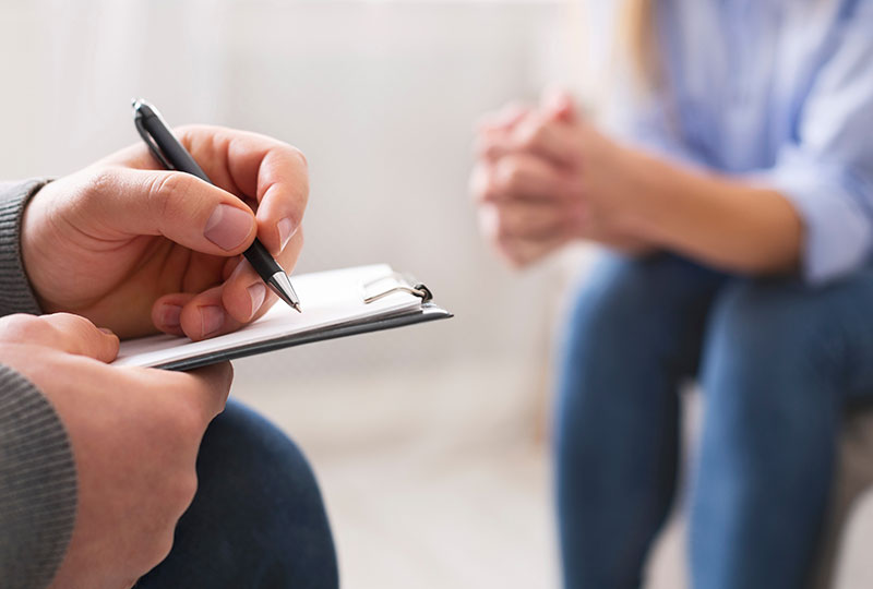 Psychologist noting problems of patient at therapy session